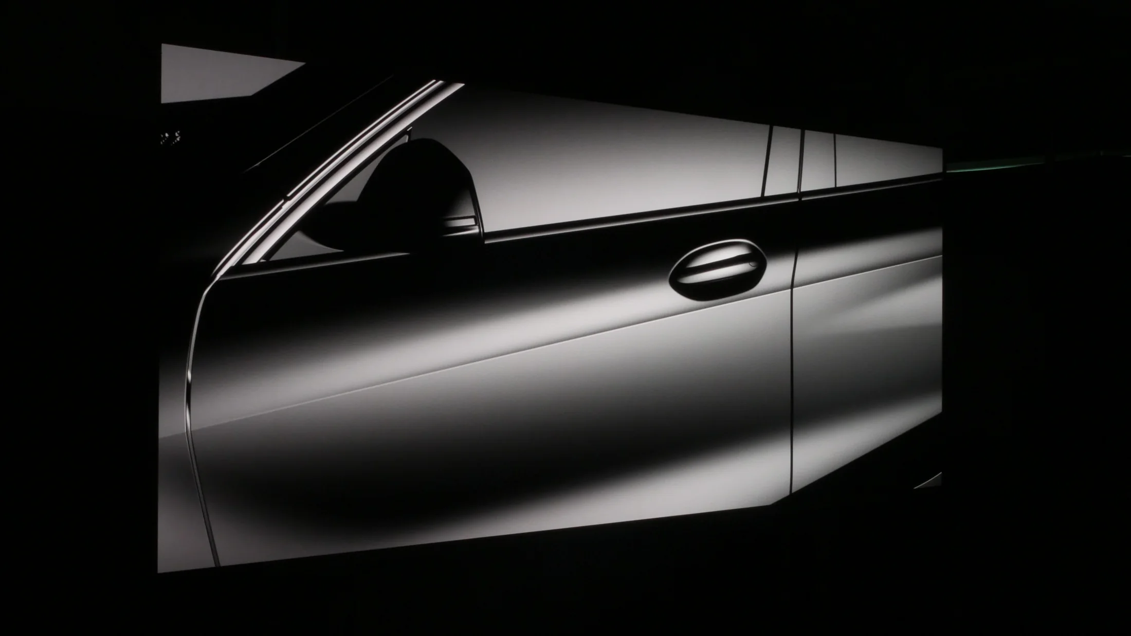 Car door rendered in pure grayscale on a large TRUE dvLED wall in a dark studio, every tone from black to white held evenly across the whole wall
