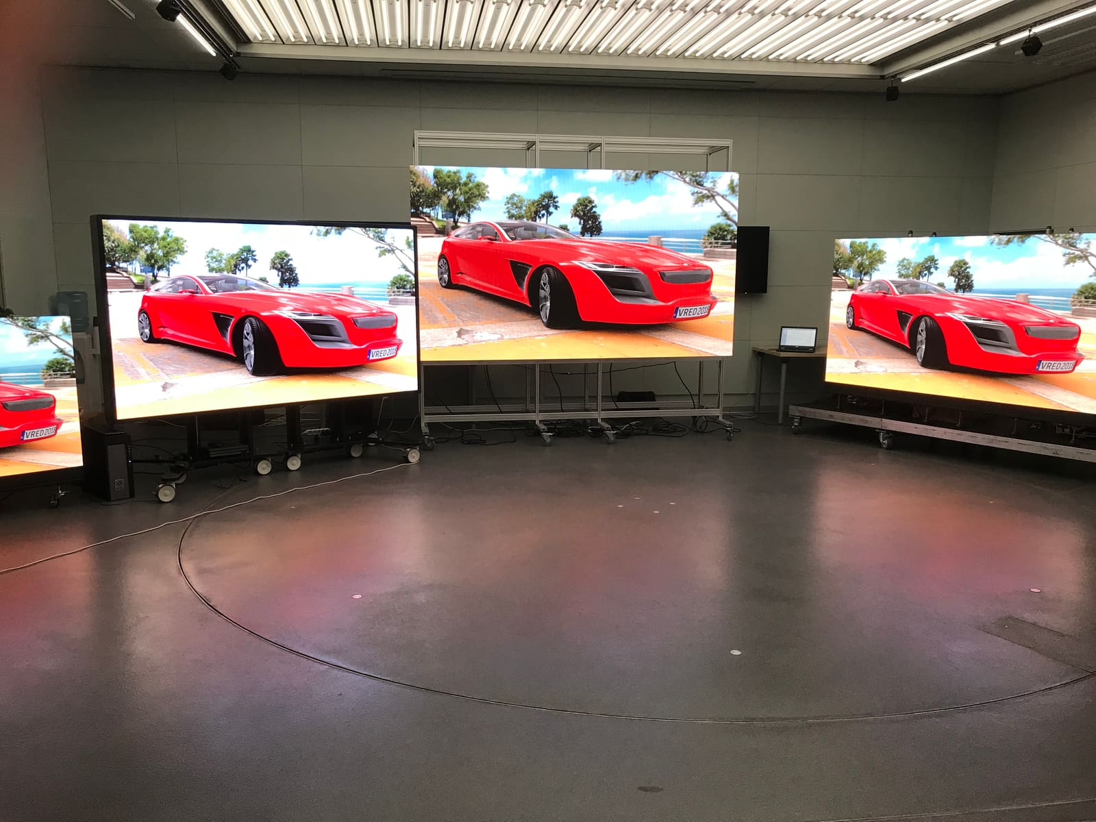 Three rolling TRUE dvLED demo dvLED walls showing a red concept car in the lab showroom