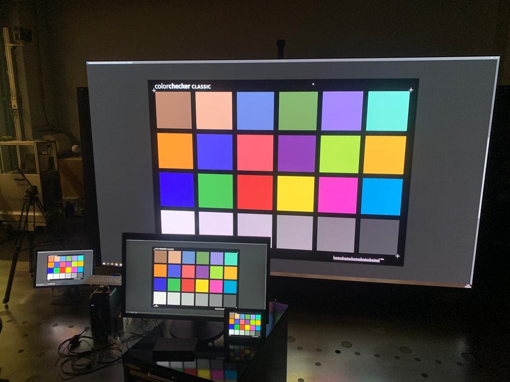 Color reference chart on a large TRUE dvLED wall beside reference monitors and a camera rig