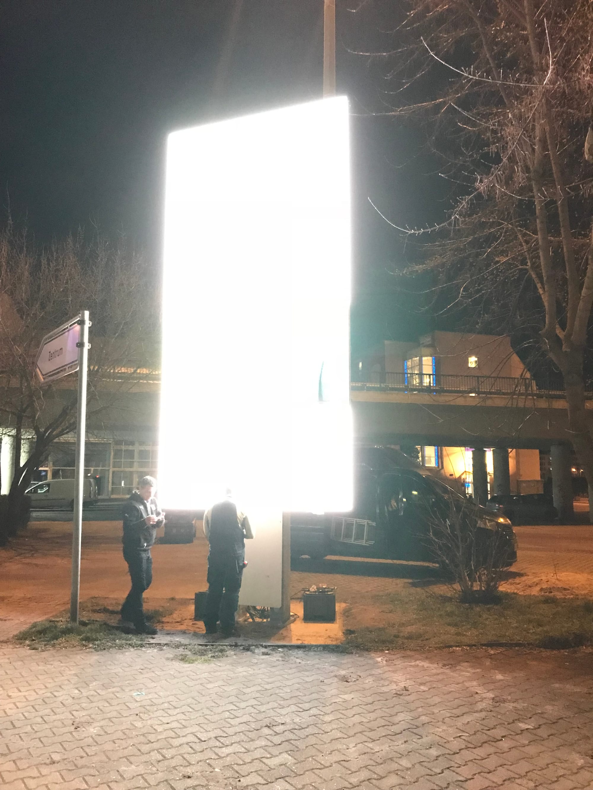 Technician standing in front of a brightly lit dvLED panel at night, the panel glowing where his head would be